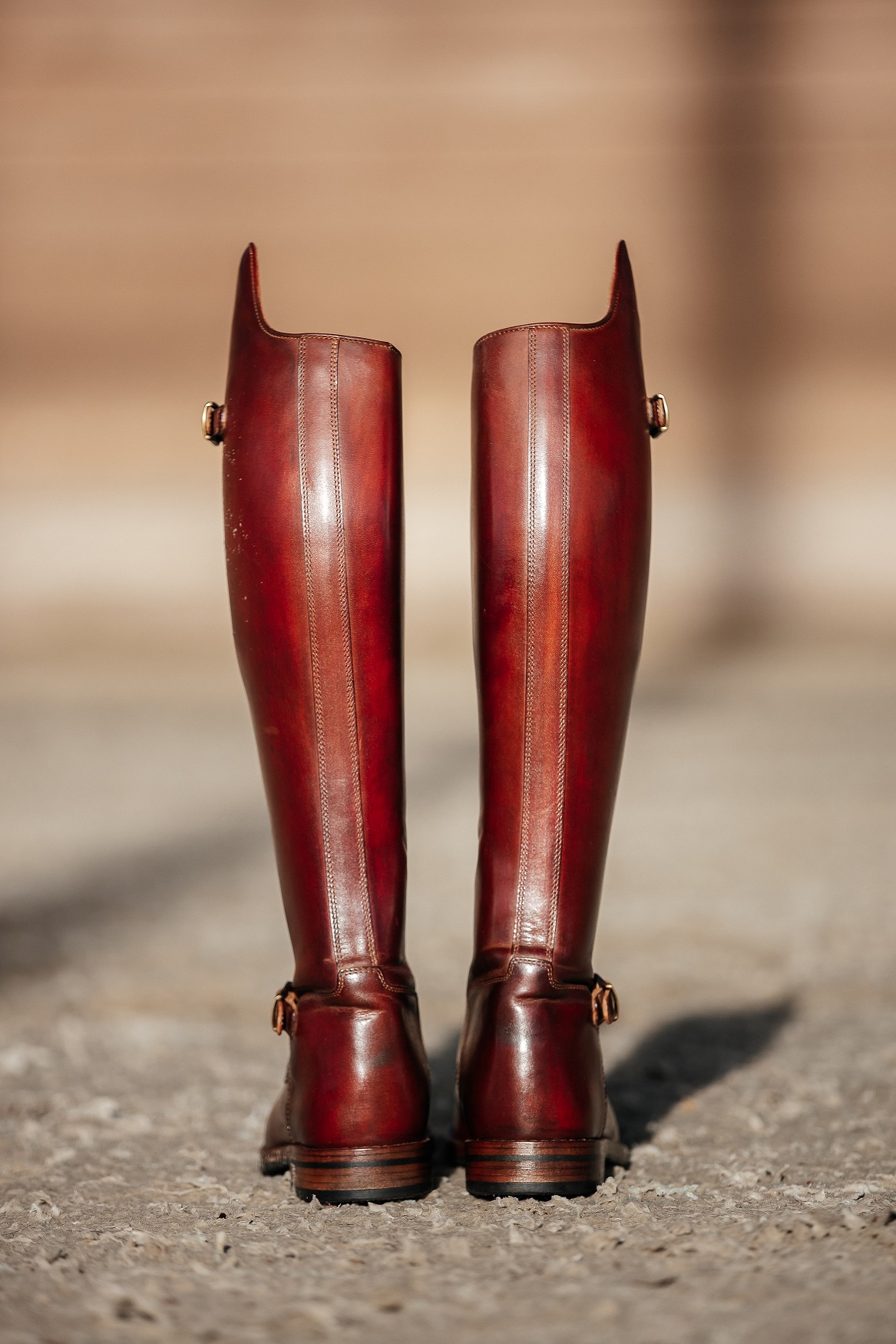 Back view of hand-patinated oxblood dressage boots with brass buckles