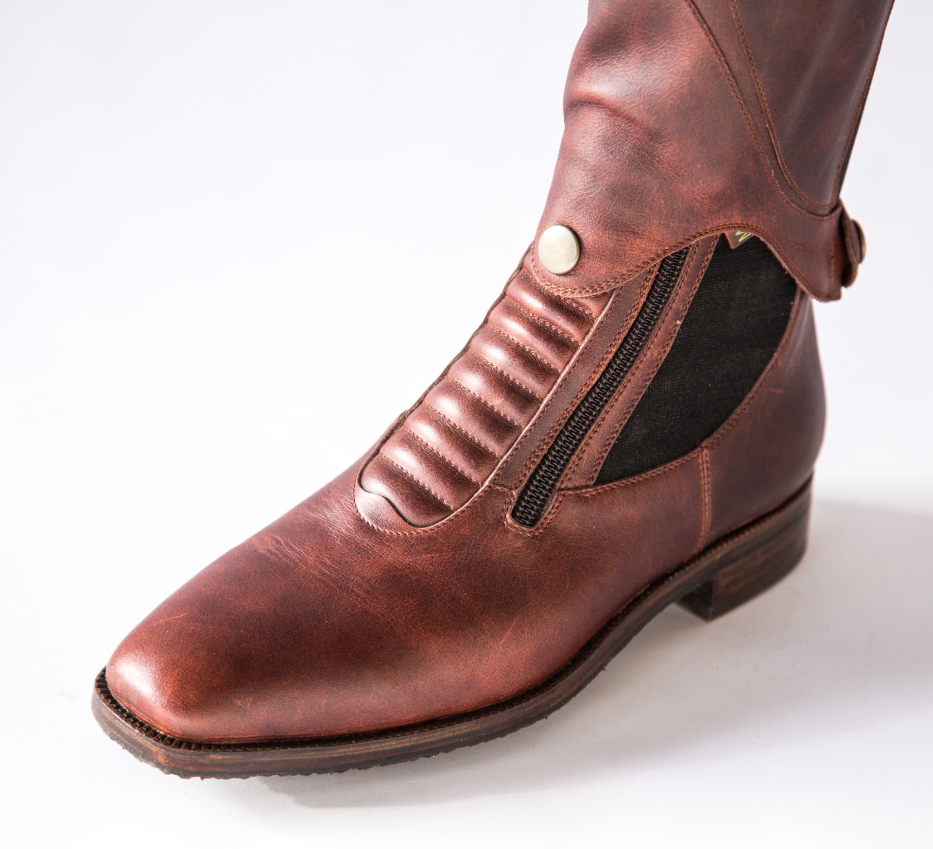 Close view of a cognac boot with ribbed panel, snap fastening and side zip