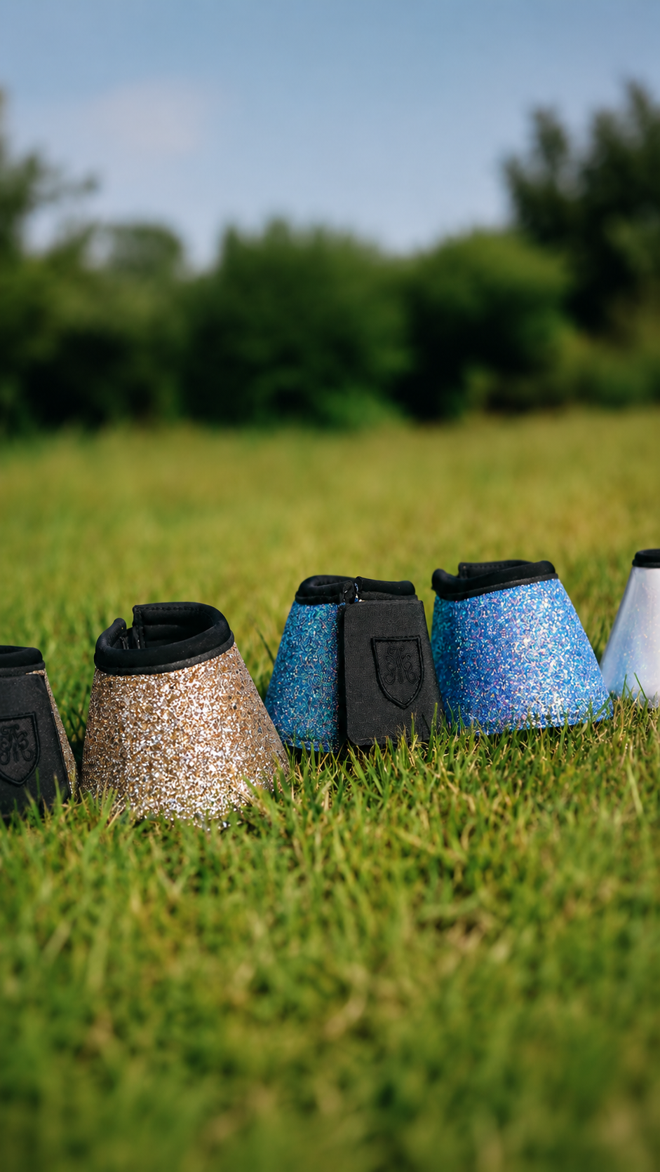 Row of glitter bell boots in gold, blue and white on grass