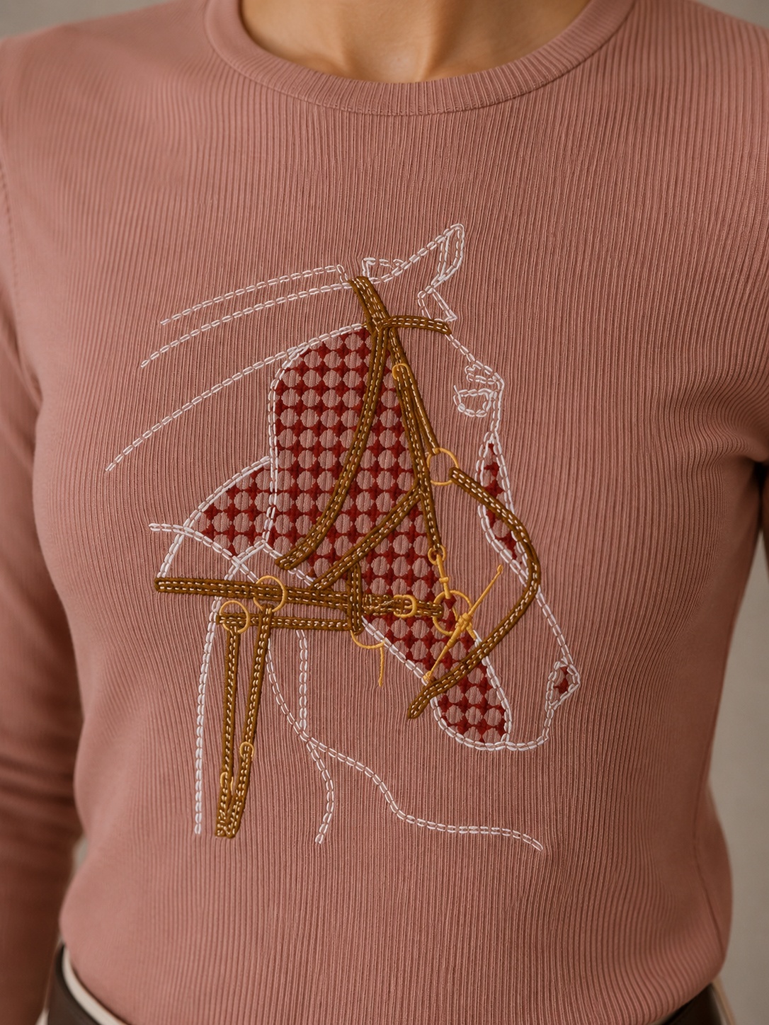Hand embroidery of a bridled horse head on a dusty rose ribbed top