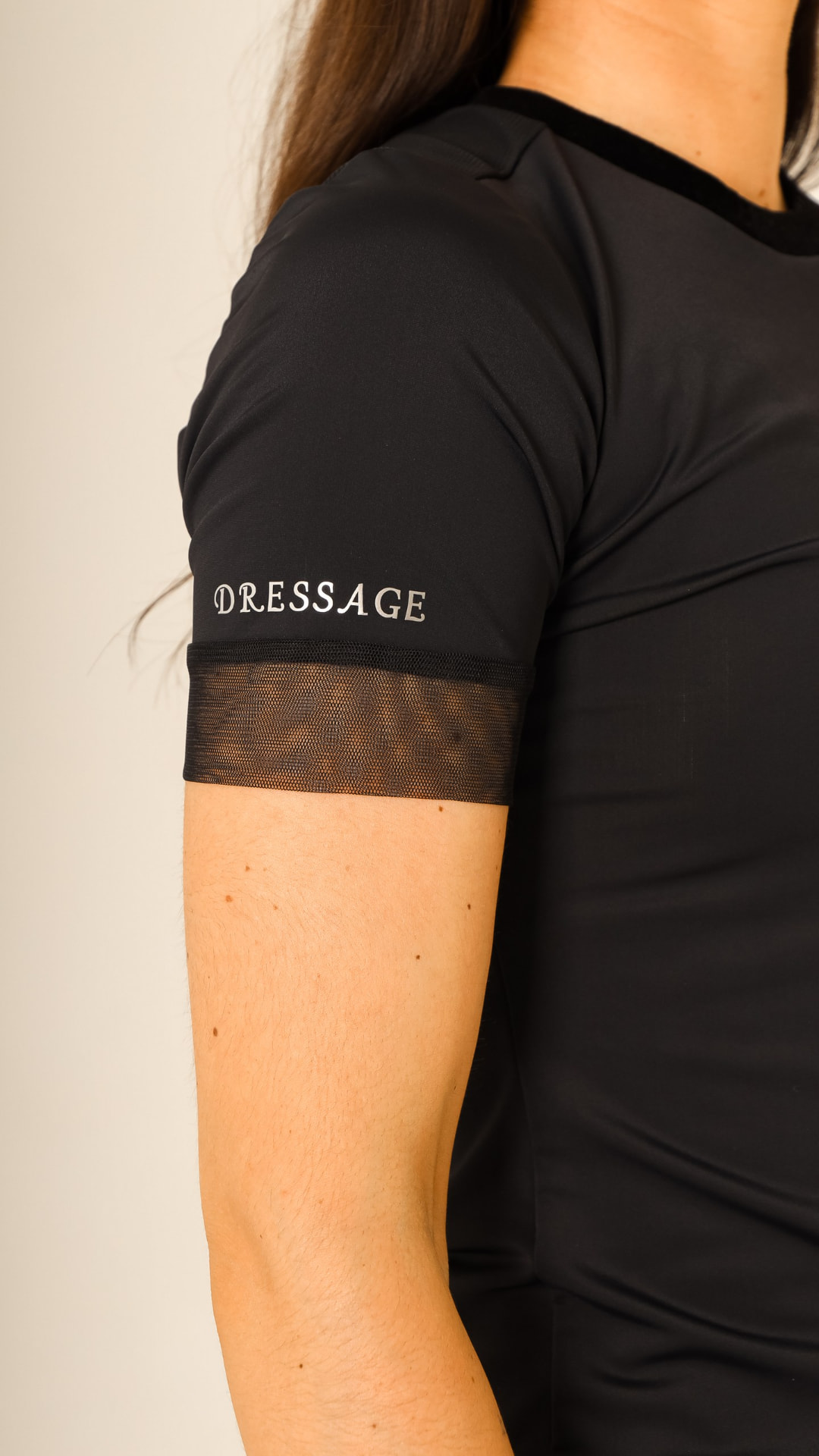 Detail of a black technical show shirt with mesh sleeve and Dressage lettering