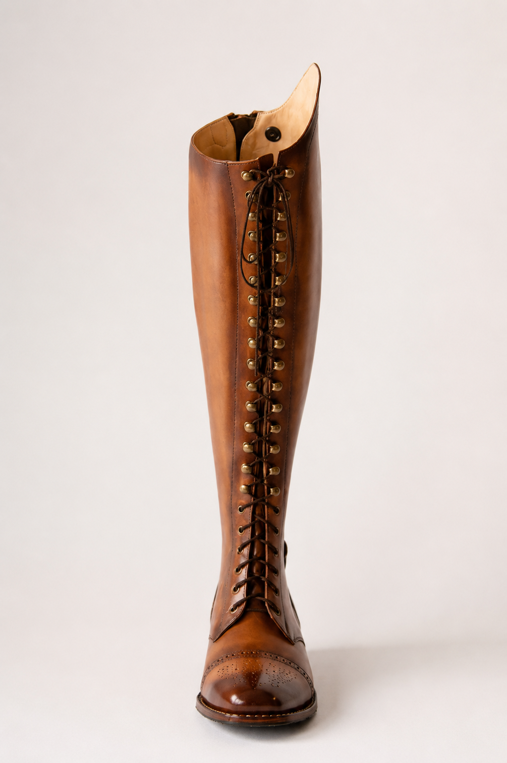 Front view of a cognac laced riding boot with brogue detailing