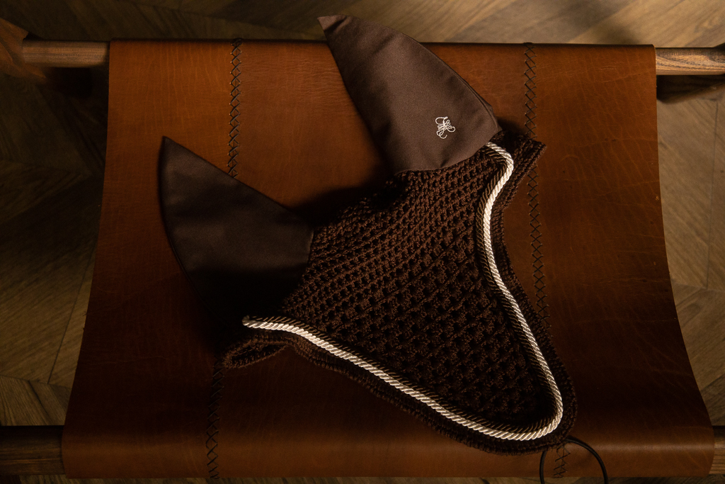 Brown crocheted fly bonnet with corded trim on a leather roll