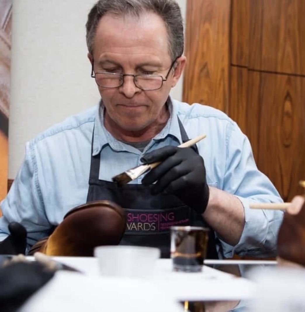 Master craftsman hand-finishing a leather boot with a brush