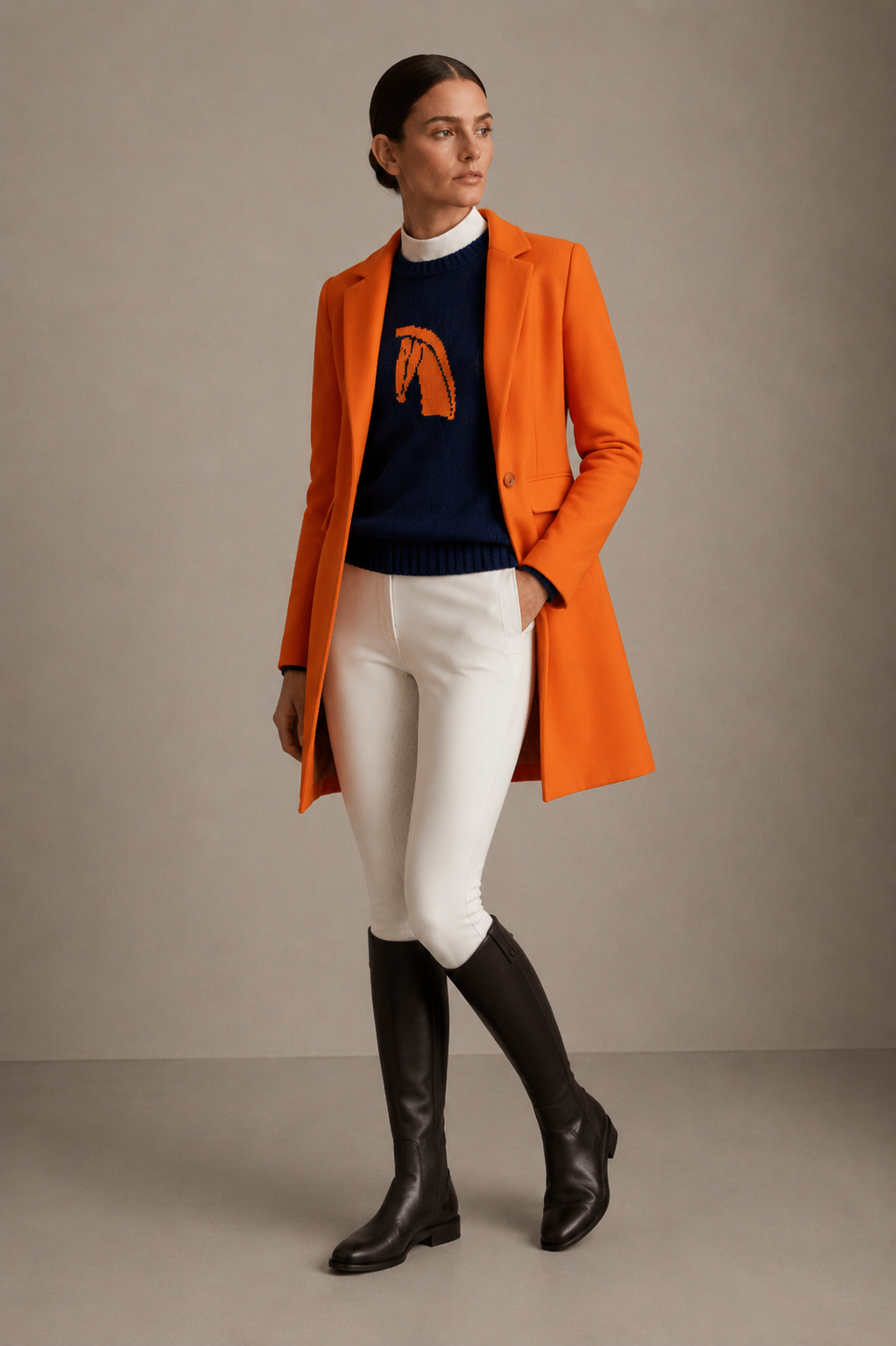 Model in an orange coat, navy horse-motif sweater, white breeches and tall boots