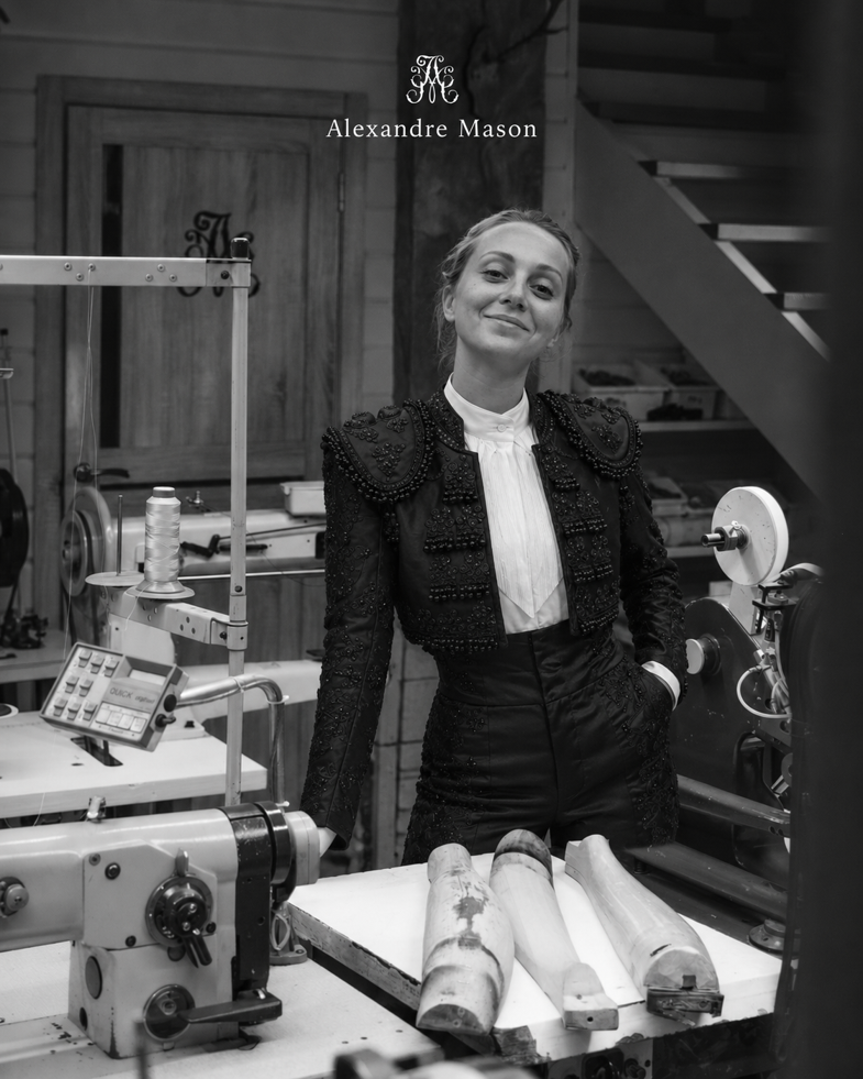 Artisan in the Alexandre Mason workshop beside a sewing machine and wooden shoe lasts, black and white