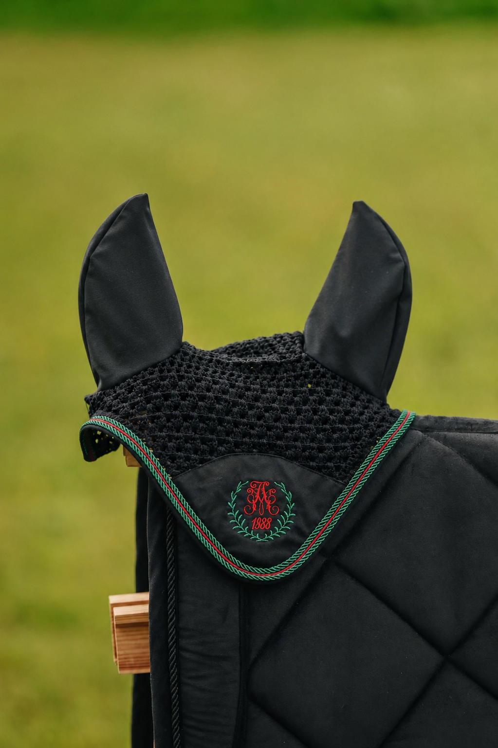Black crocheted fly bonnet with green and red corded trim and monogram