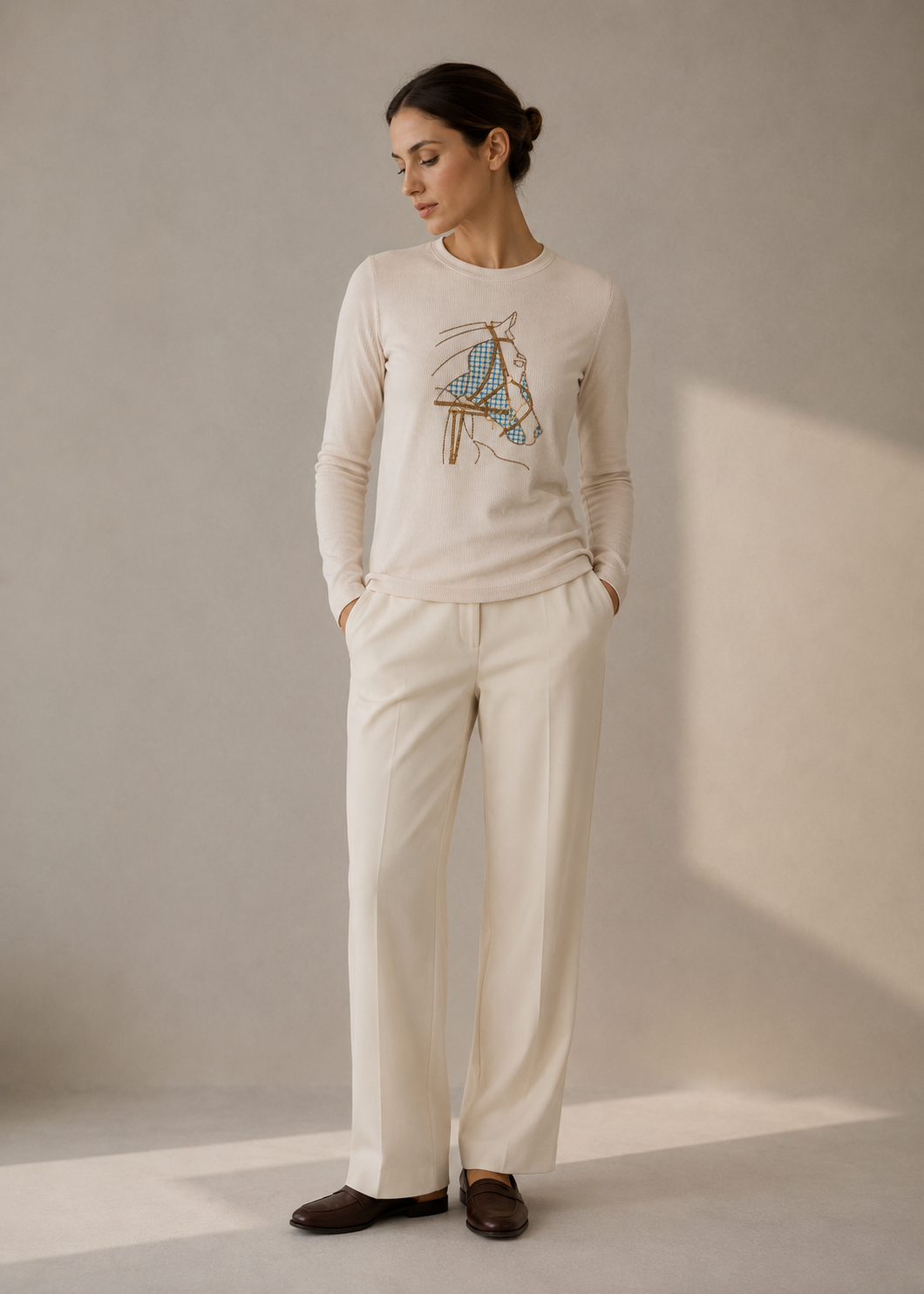 Model in an ivory bridle-motif knit top with cream trousers