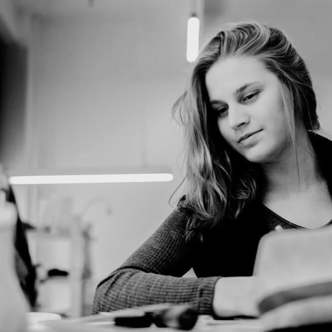 Technologist guiding the technical development of a piece — focused at the workbench